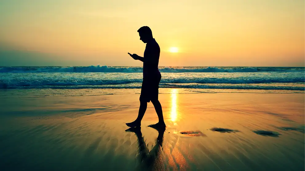 mand på strand med mobil